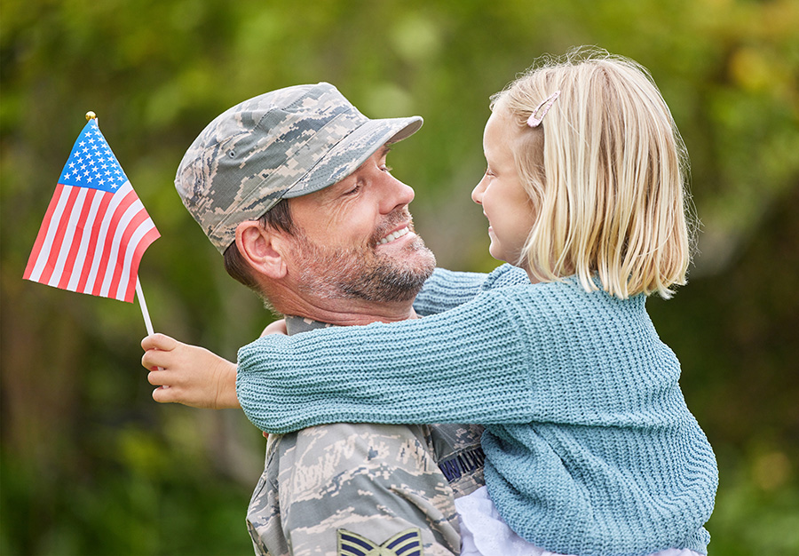 Photo of military veteran holding daughter with American flag.