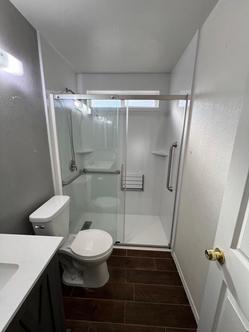 Photo of remodeled stand-up shower, toilet and sink.